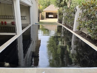 Black epoxy and urethane coating on Dallas driveway with 2 open garage doors and house.