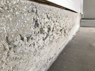 Concrete damage in a garage that needs to be repaired.